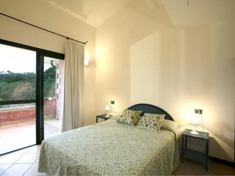 Une chambre lumineuse avec un grand lit et un accès à une terrasse.