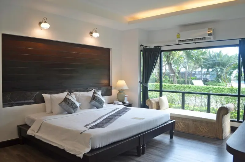 Une chambre lumineuse avec un grand lit et une vue sur la végétation.