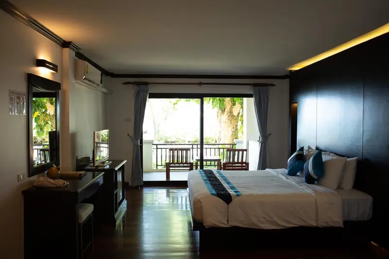 Une chambre lumineuse avec un grand lit et un accès à un balcon.