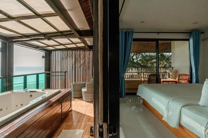 Une chambre lumineuse s'ouvre sur une terrasse avec jacuzzi.