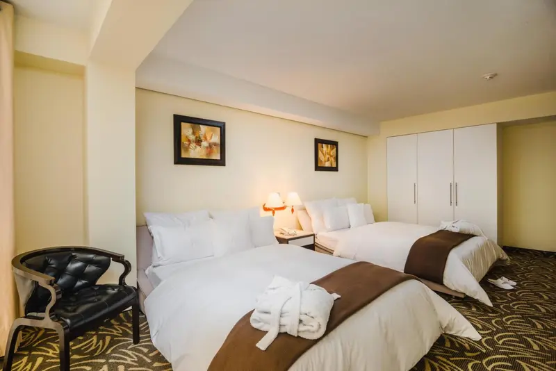 Chambre lumineuse avec deux lits et décoration murale.