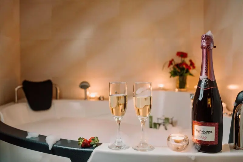 Une baignoire remplie d'eau avec une bouteille de champagne et deux verres.