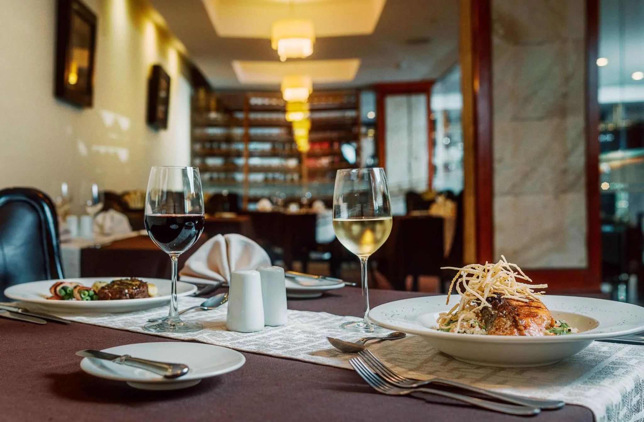 Une table est dressée avec des plats et des verres de vin dans une salle à manger.
