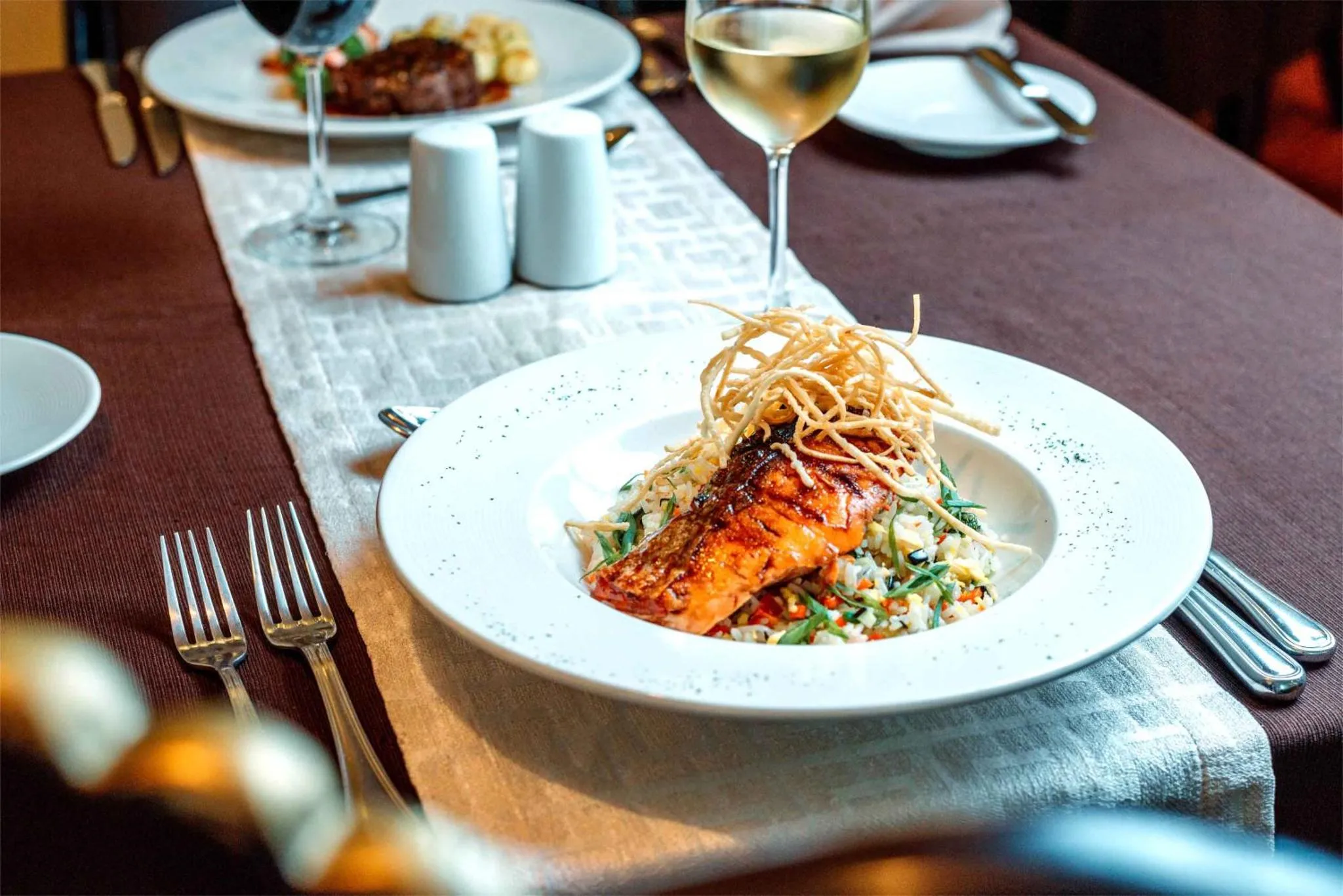 Une table est dressée avec des plats de poisson et des verres de vin.
