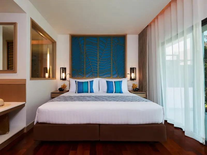 Une chambre lumineuse avec un grand lit recouvert d'une courtepointe blanche et bleue.