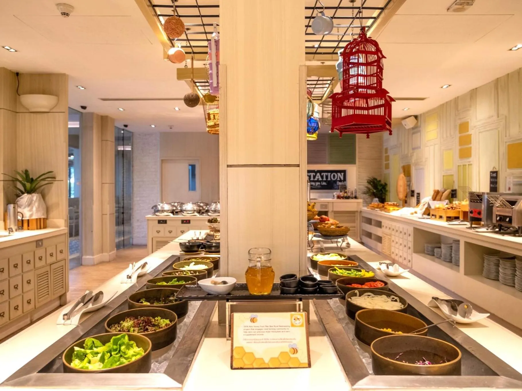 Un buffet propose une variété de plats et de salades dans une salle lumineuse.