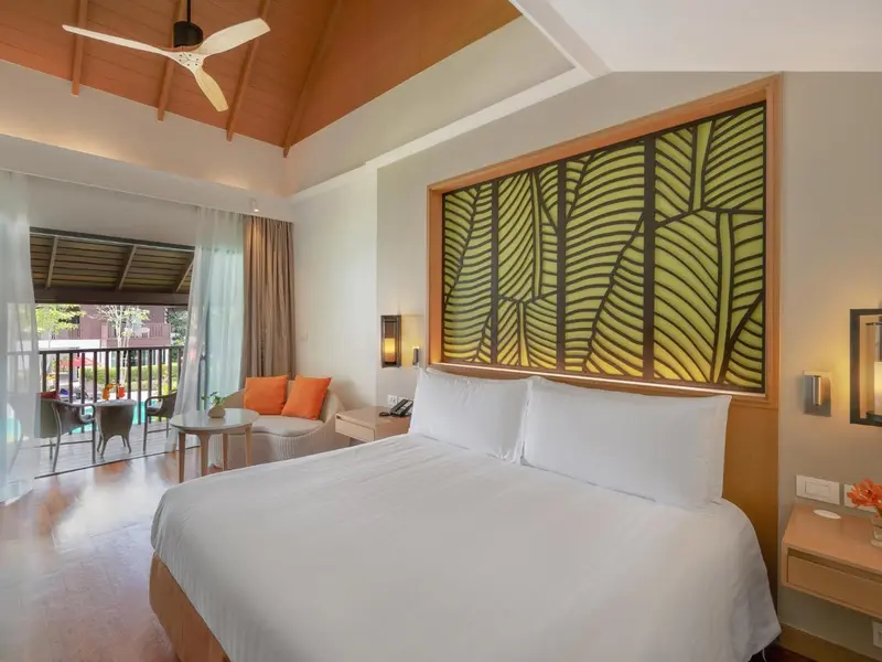 Une chambre lumineuse avec un grand lit et un coin salon donnant sur une terrasse.