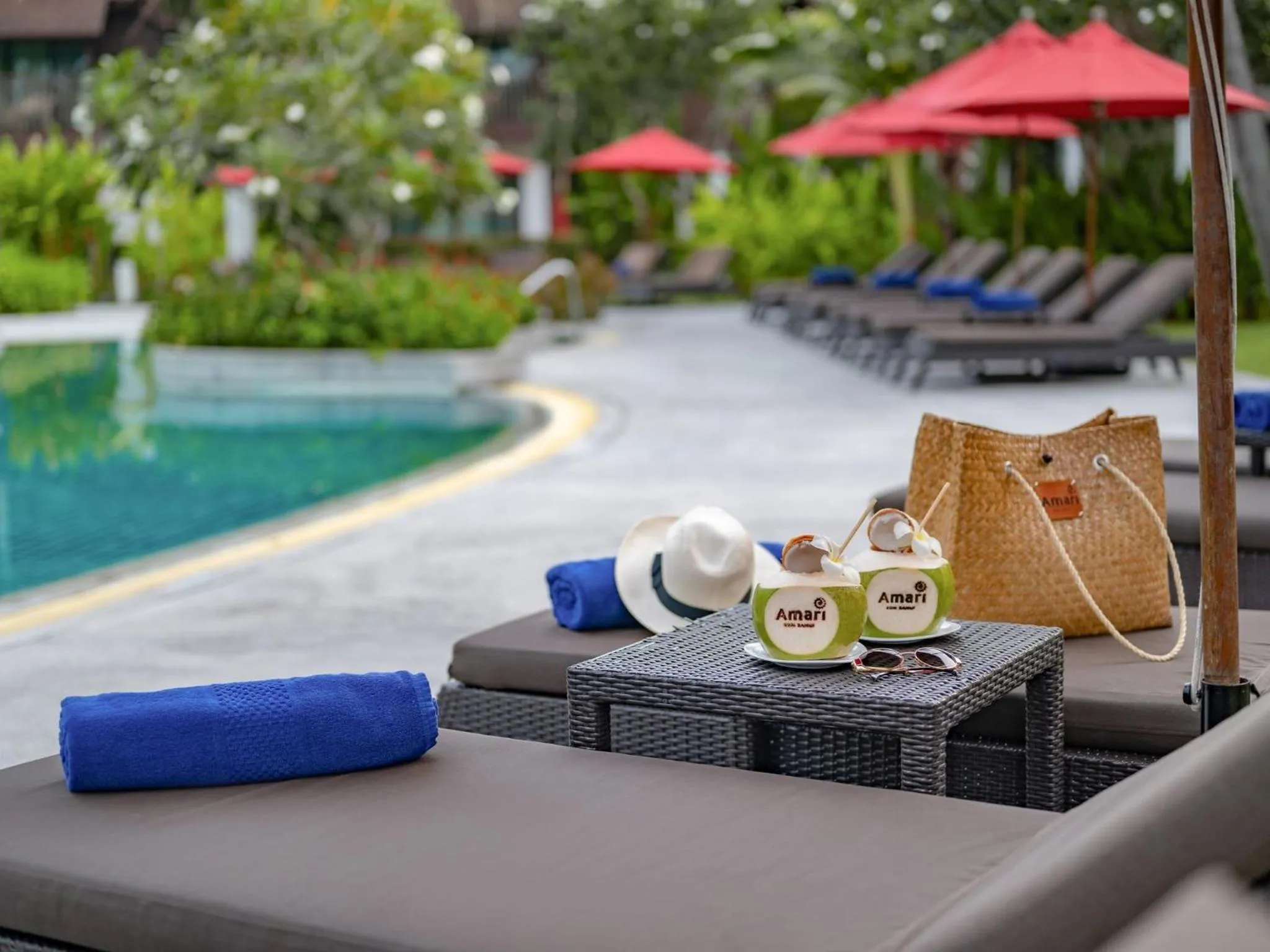 Transats au bord d'une piscine avec des boissons et des serviettes.