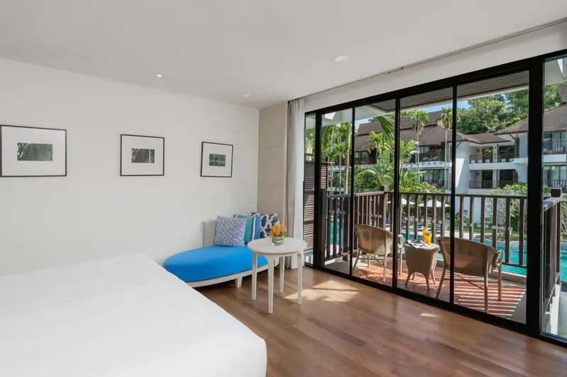 Une chambre lumineuse s'ouvre sur une terrasse avec vue sur la végétation.