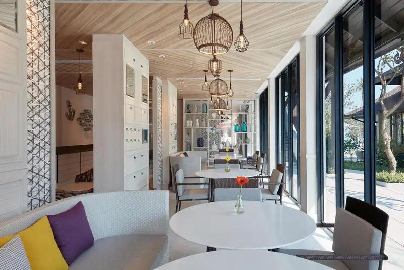 Espace de détente lumineux avec mobilier blanc et touches colorées.