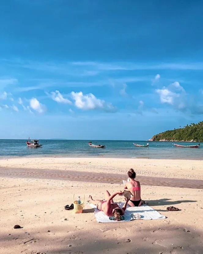 Personnes se relaxant sur une plage de sable fin face à la mer.