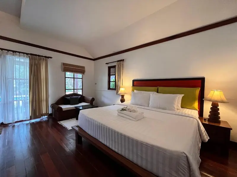 Une chambre lumineuse avec un grand lit et un fauteuil.