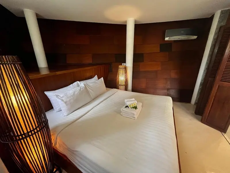 Une chambre lumineuse avec un grand lit recouvert de draps blancs et de coussins.