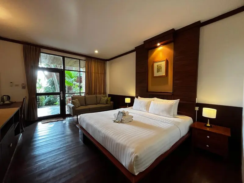 Une chambre lumineuse avec un grand lit et un coin salon.