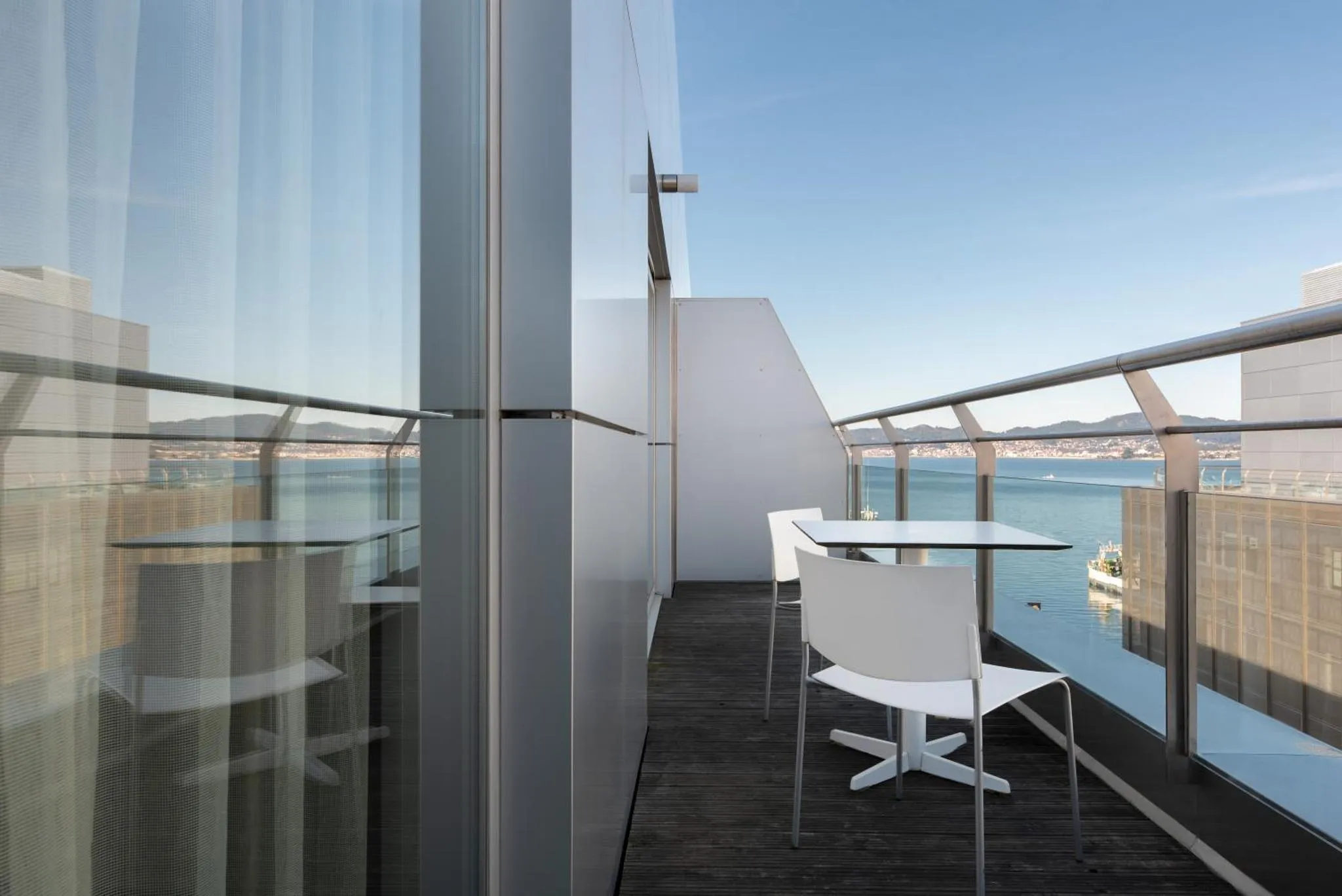 Terrasse avec mobilier blanc et vue sur la mer.