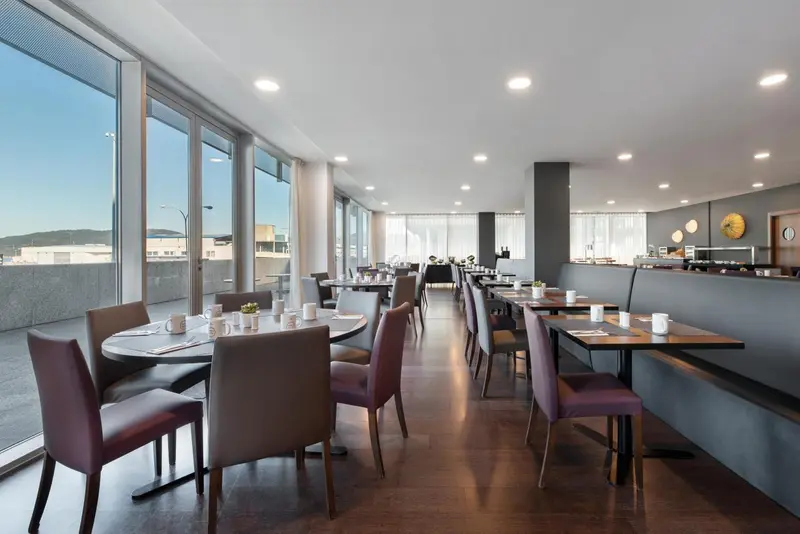 Une salle lumineuse avec des tables et des chaises est prête pour le service.