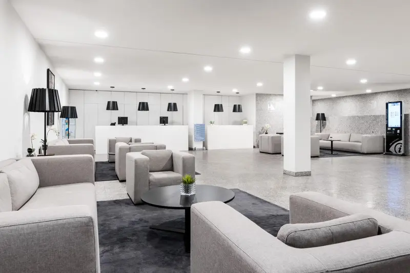 Espace d'attente lumineux avec canapés et comptoir d'accueil.