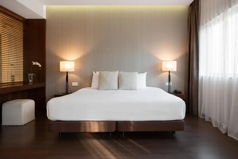 Une chambre lumineuse avec un grand lit et des lampes de chevet.