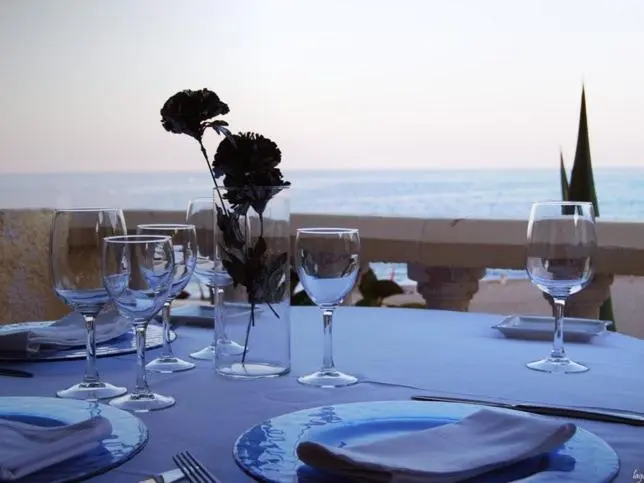 Une table dressée avec des verres et de la vaisselle face à la mer.
