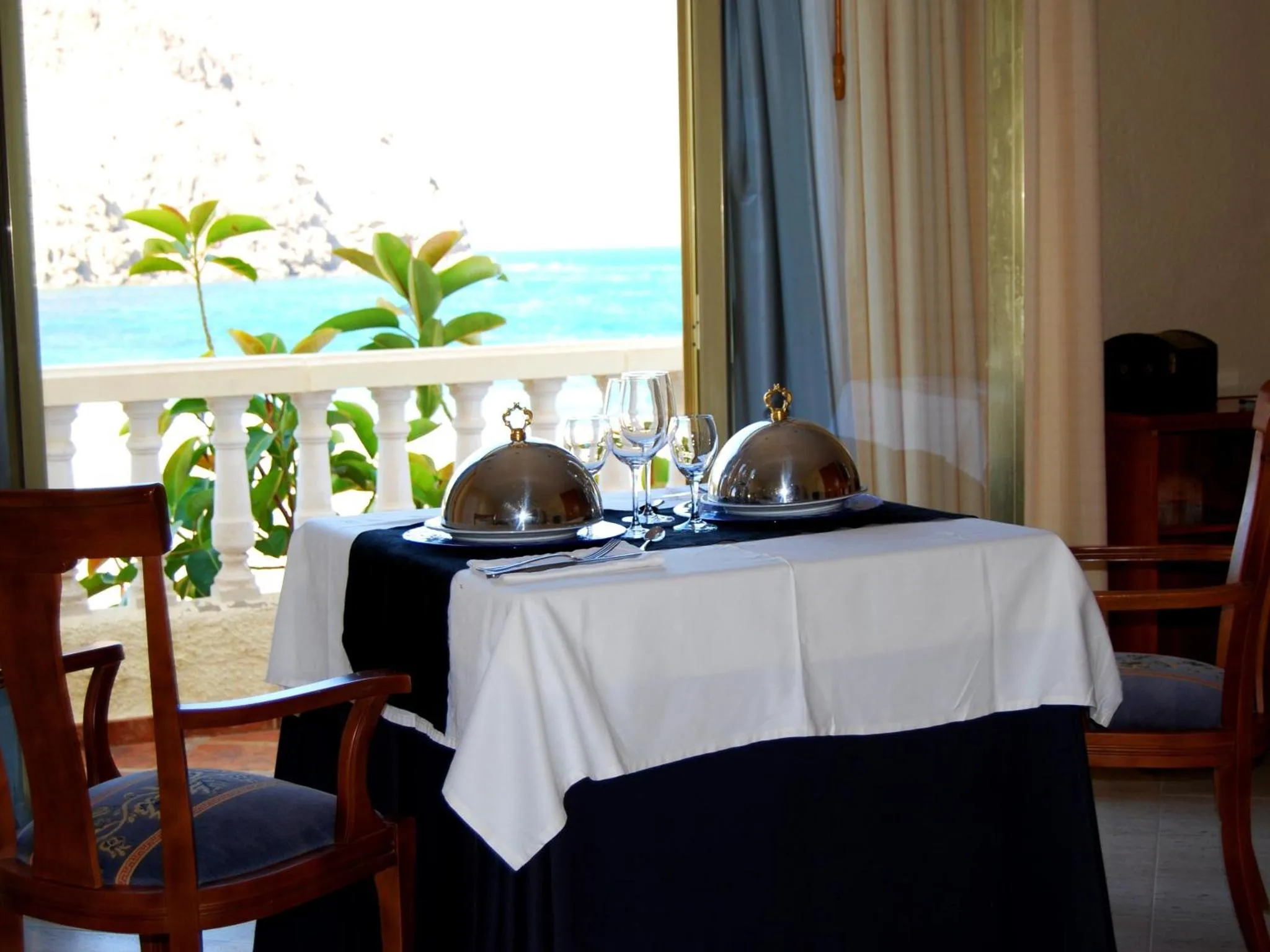Table dressée avec des plats couverts donnant sur une vue sur la mer.