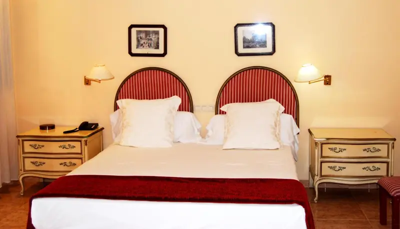 Une chambre avec un grand lit recouvert d'une courtepointe rouge et de coussins blancs.