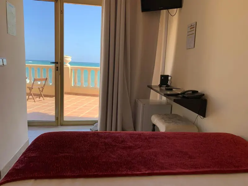 Une chambre avec vue sur la mer depuis un balcon.