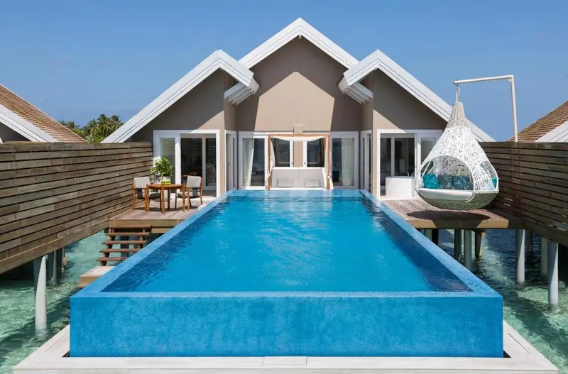 Villa sur pilotis avec piscine privée et mobilier de jardin.