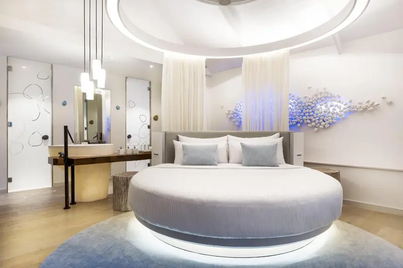 Chambre lumineuse avec un grand lit rond et une décoration moderne.