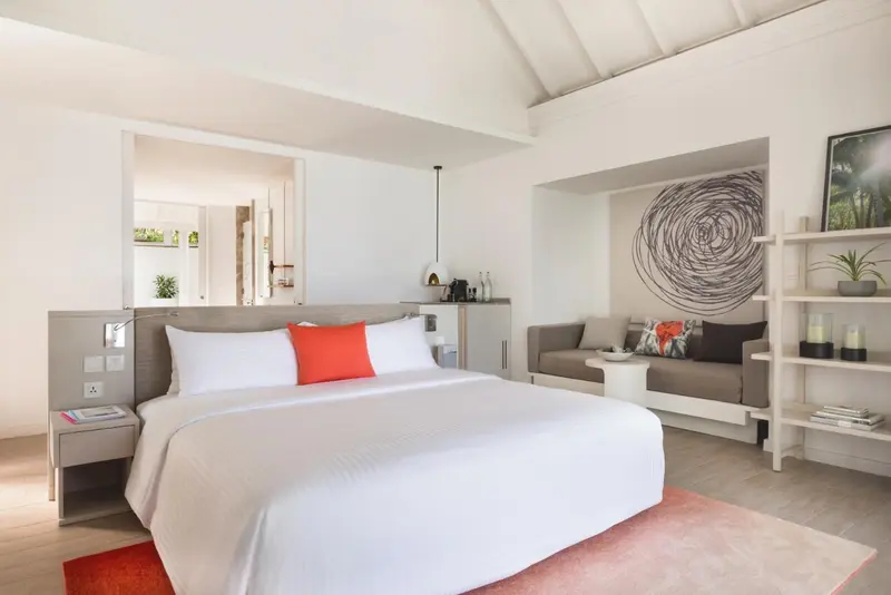 Une chambre lumineuse avec un grand lit et un coin salon.
