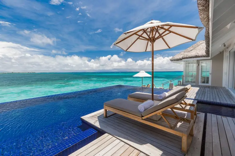 Terrasse avec transats et piscine à débordement donnant sur l'océan.