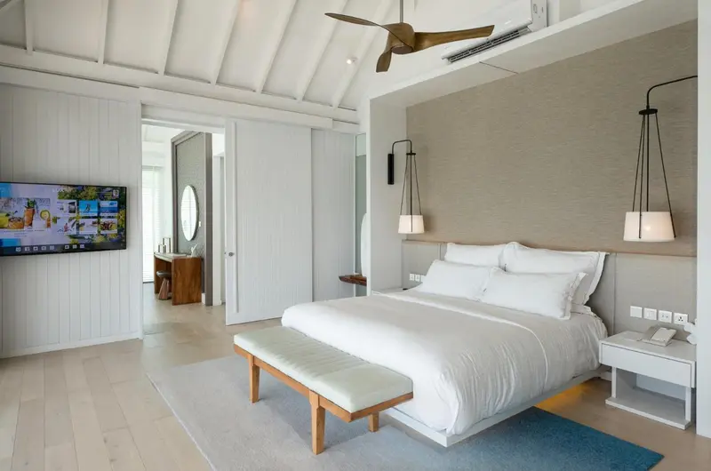 Une chambre lumineuse avec un grand lit recouvert de blanc.