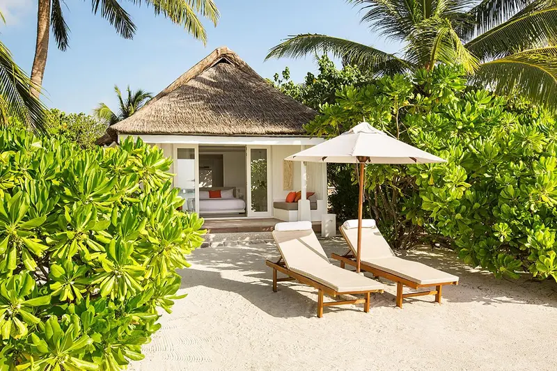 Deux transats invitent à la détente devant un bungalow de plage.