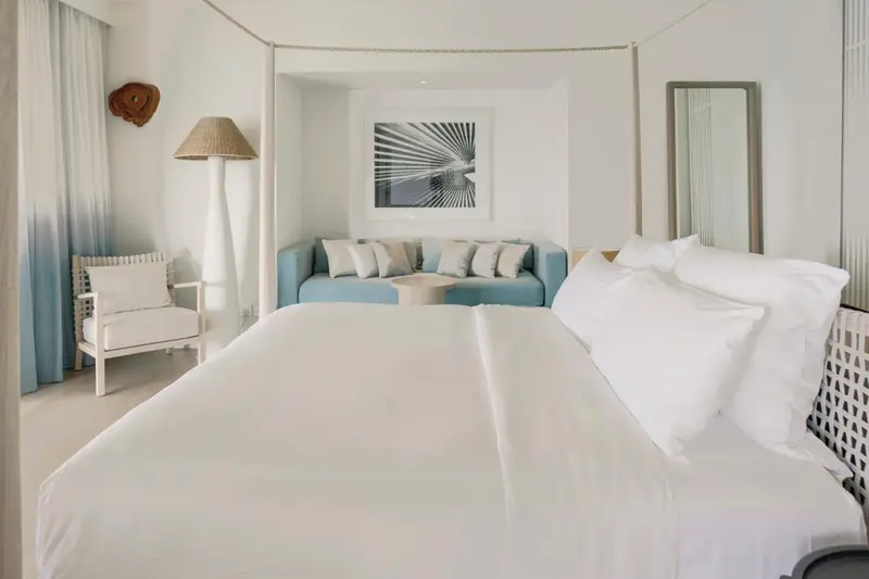 Une chambre lumineuse avec un grand lit et un coin salon.