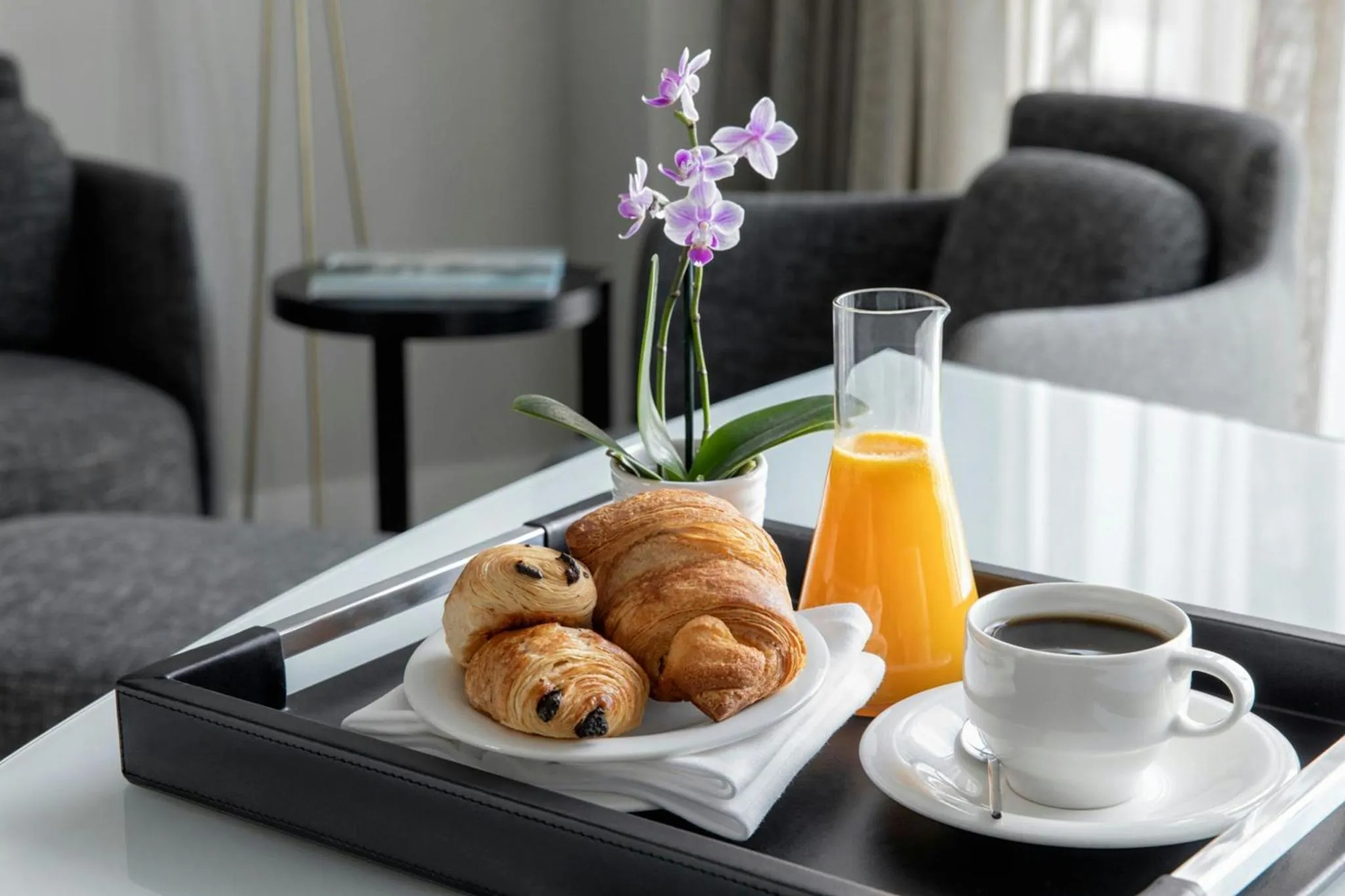 Un plateau de petit-déjeuner avec des viennoiseries et une boisson est présenté sur une table.