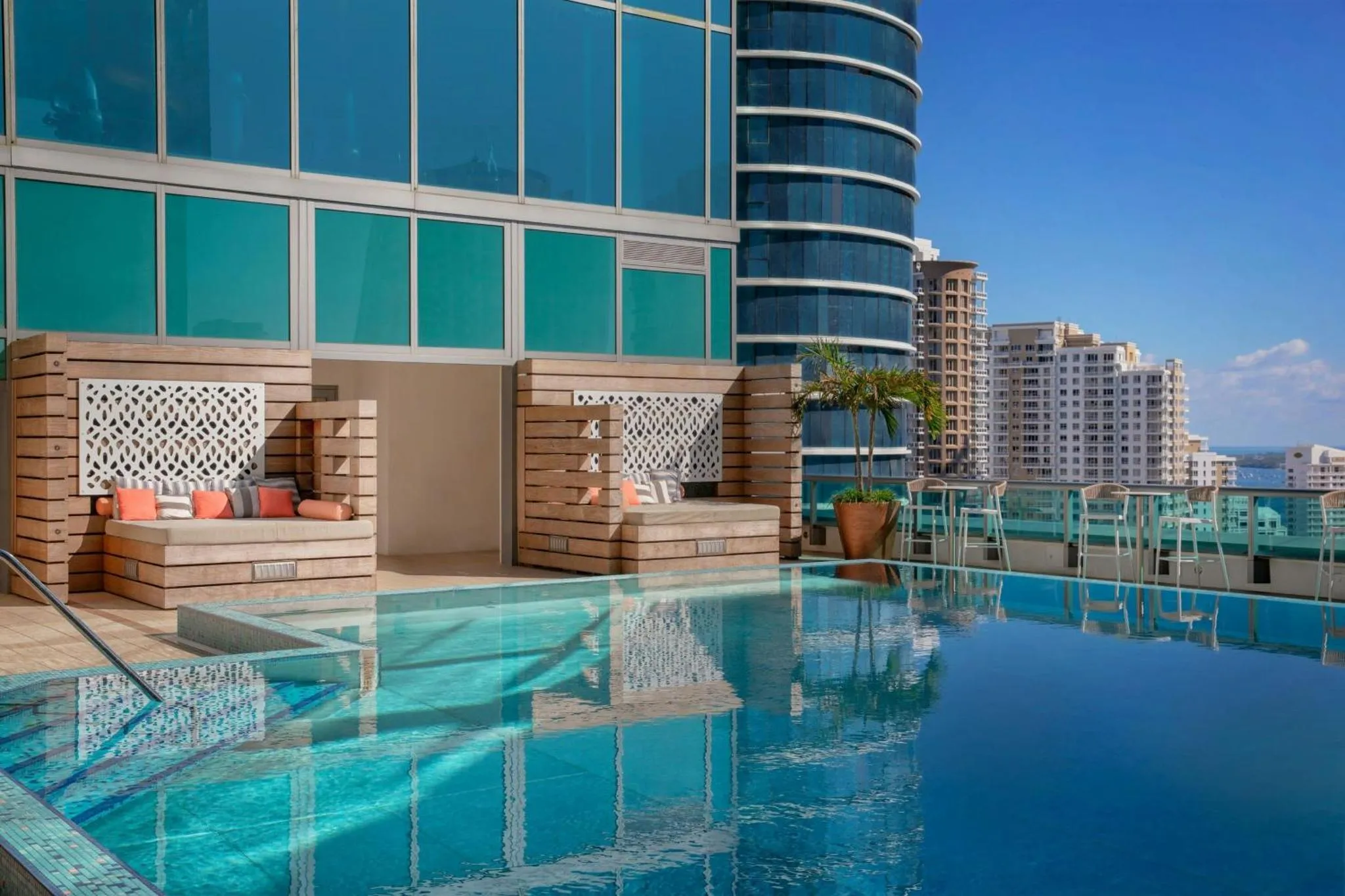 Une piscine à débordement avec des salons confortables et une vue sur la ville.