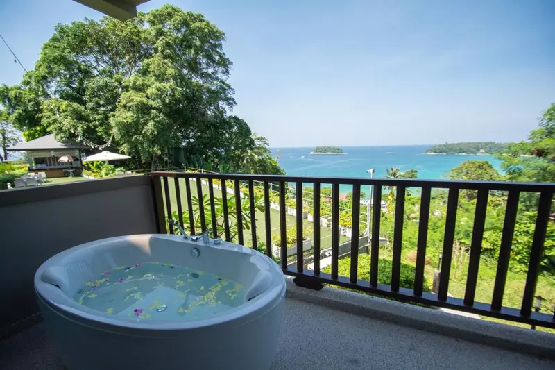Baignoire sur une terrasse avec vue sur la mer et la végétation.