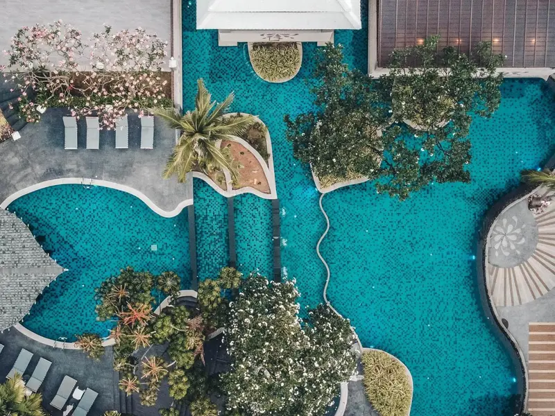 Vue aérienne d'une piscine sinueuse entourée de végétation tropicale.