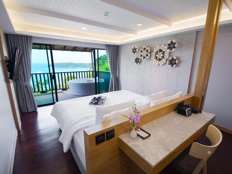 Chambre lumineuse avec un grand lit et une baignoire sur le balcon.