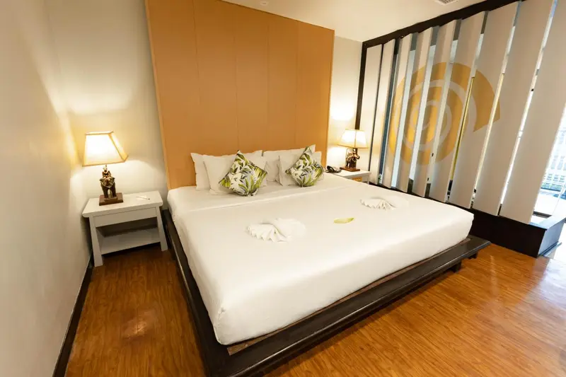 Une chambre lumineuse avec un grand lit recouvert de draps blancs et de coussins.