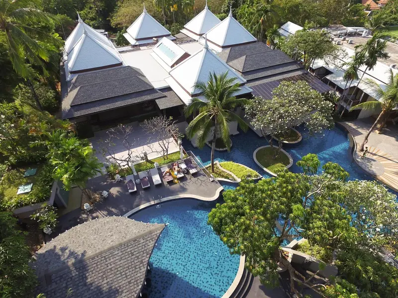Vue aérienne d'un complexe hôtelier avec piscine et végétation tropicale.