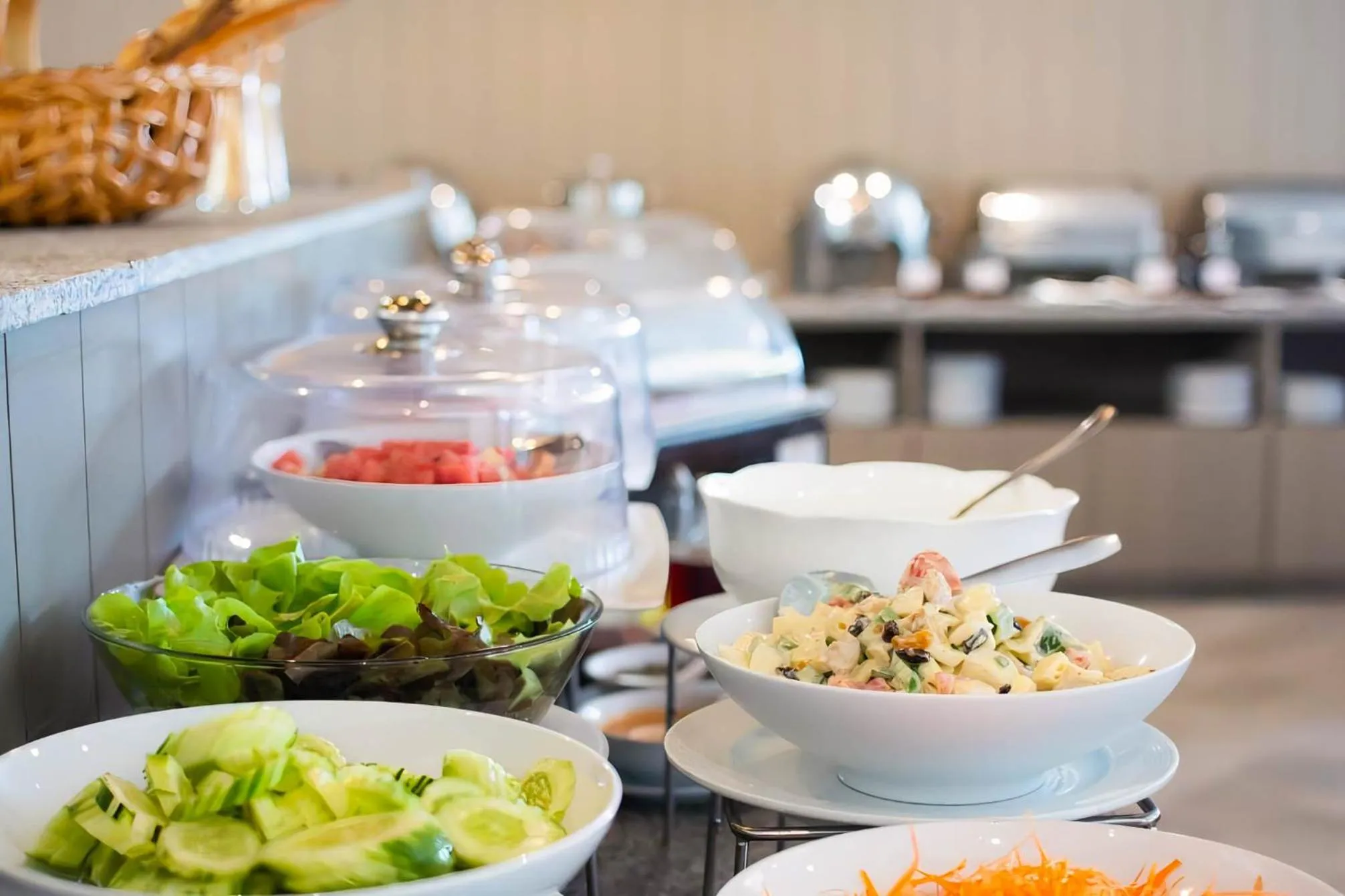 Un buffet propose des salades et des plats variés dans un espace lumineux.