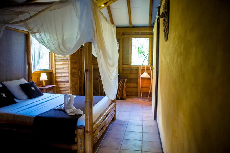 Une chambre avec un lit à baldaquin et une décoration tropicale.