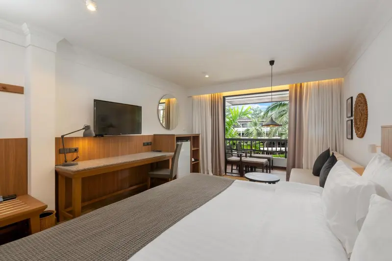 Une chambre lumineuse avec un lit confortable et un bureau donnant sur une terrasse.