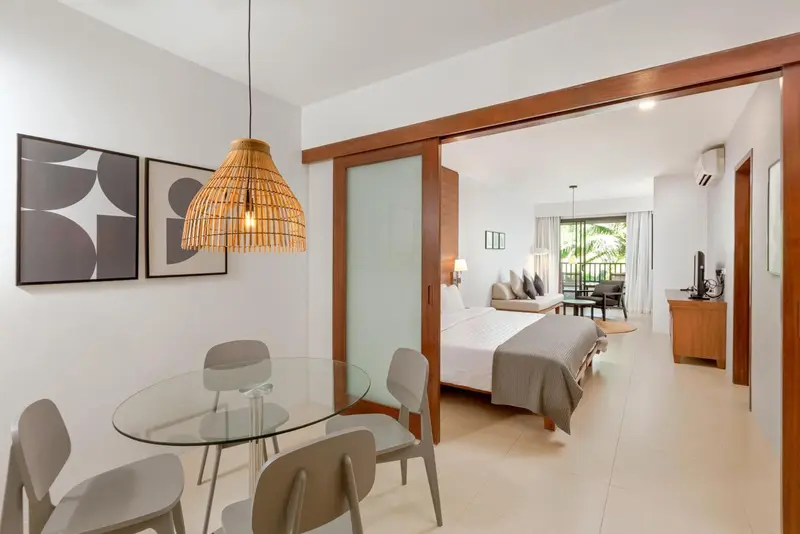 Une salle à manger lumineuse s'ouvre sur une chambre avec un lit confortable.