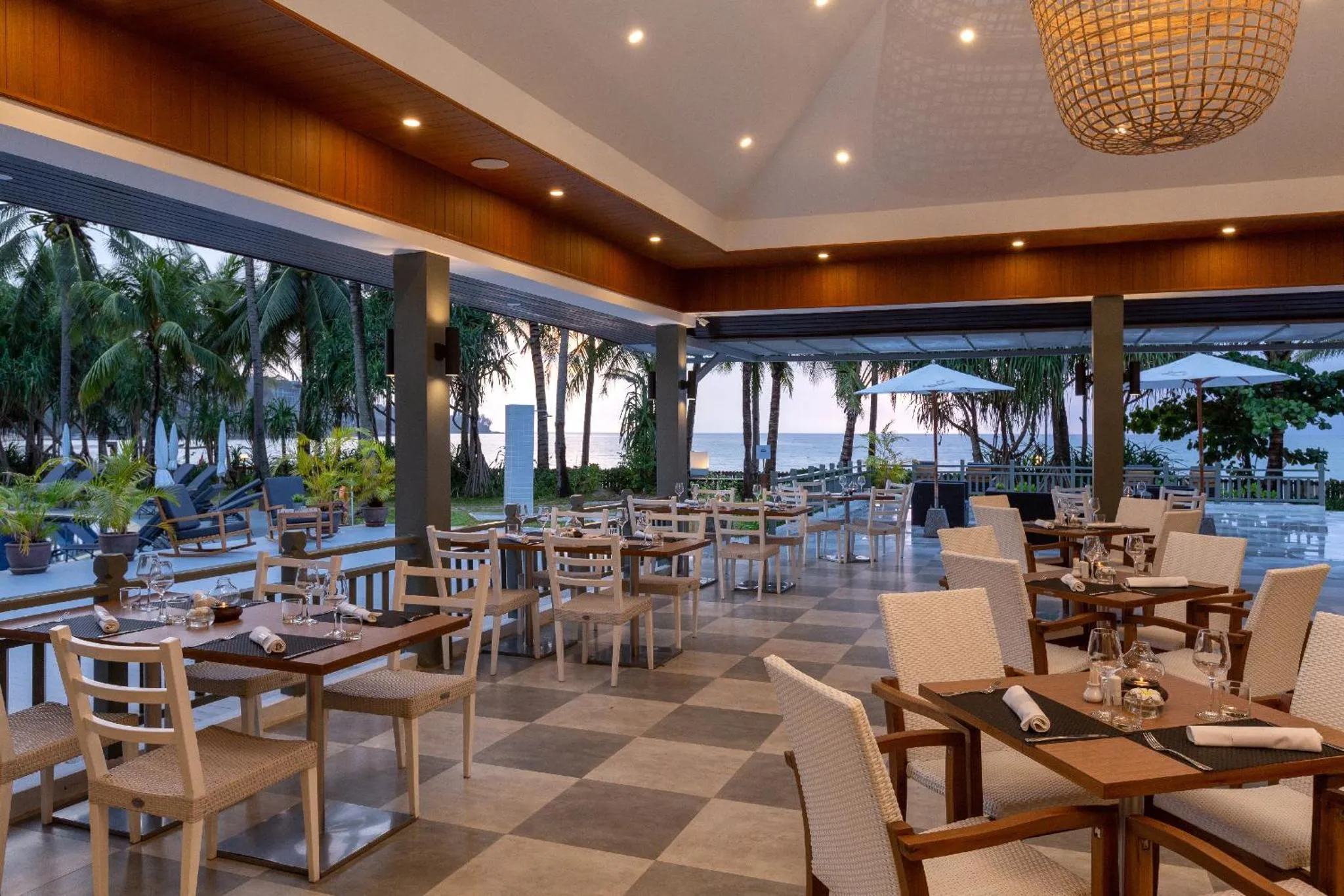 Une salle à manger lumineuse avec des tables dressées face à une plage.