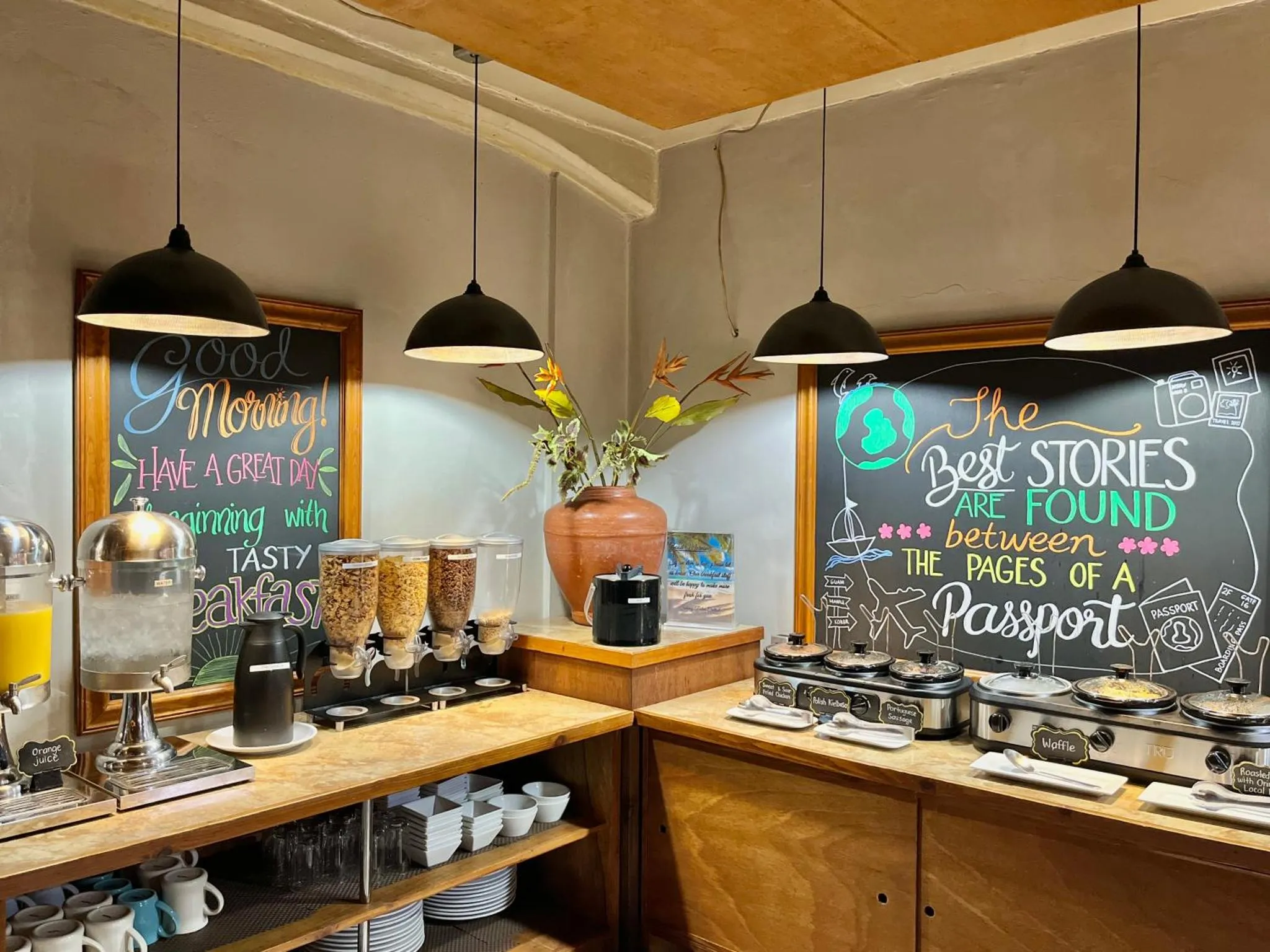 Un buffet propose des céréales, des gaufres et des boissons dans une salle lumineuse.