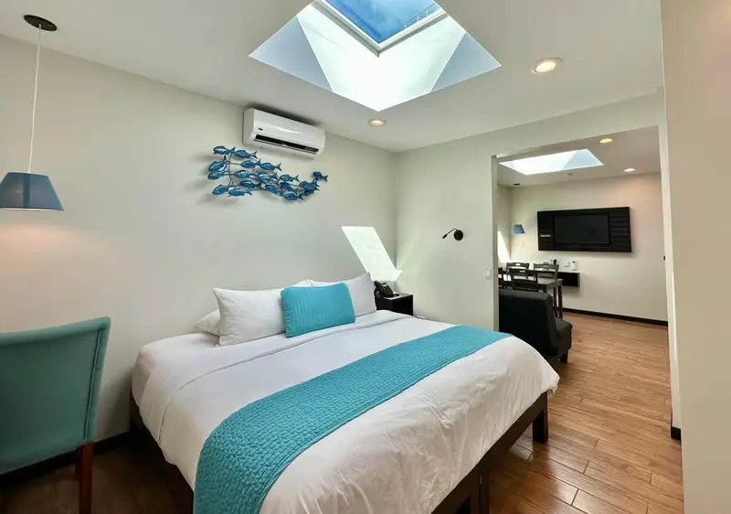 Une chambre lumineuse avec un lit fait et un espace repas attenant.