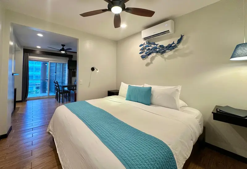 Une chambre lumineuse avec un grand lit recouvert d'une couverture turquoise.