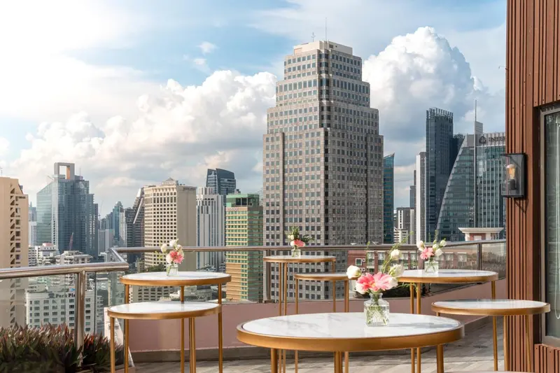 Tables rondes fleuries sur une terrasse avec vue sur la ville.