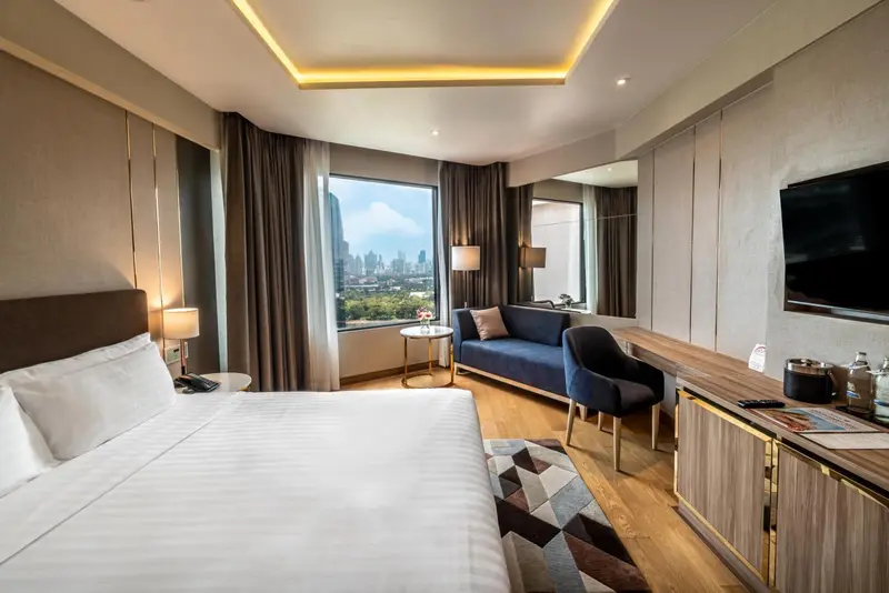 Une chambre lumineuse avec un lit, un canapé et une vue sur la ville.